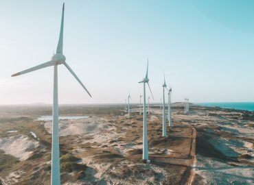 a row of wind turbines next to the ocean
