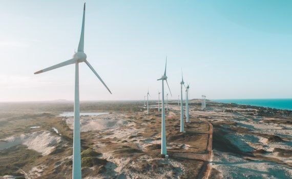 a row of wind turbines next to the ocean