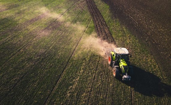 green and white tractor on green grass field during daytime